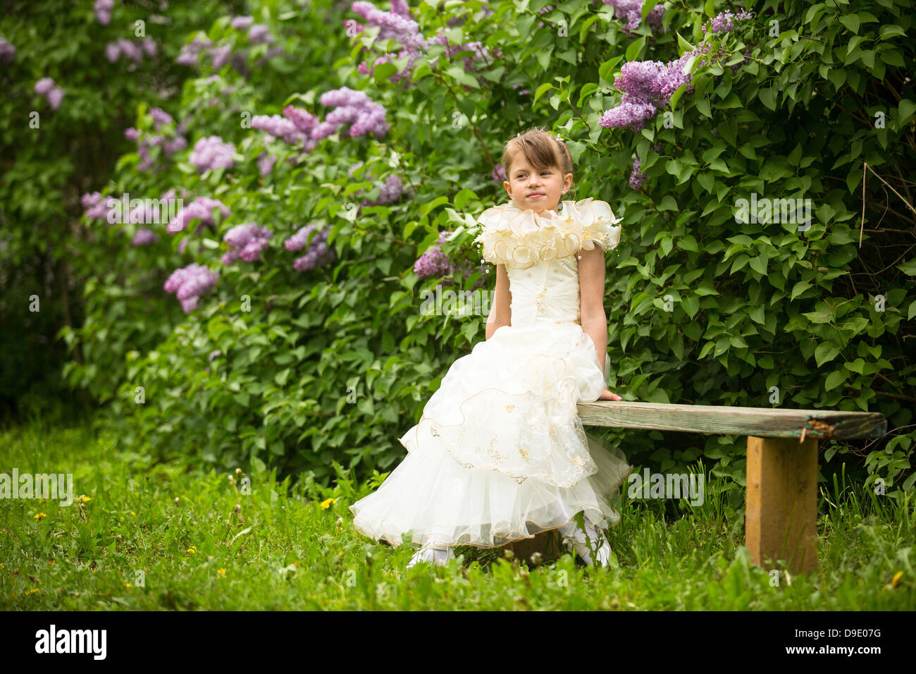 Schöne Mädchen sitzen auf einer Bank im Garten. Stockfoto