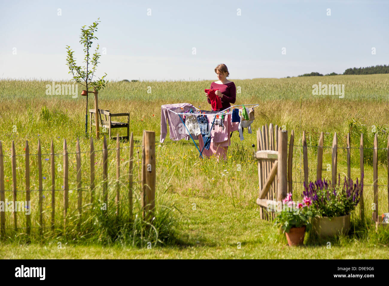 Junge Frau Aufhängen der Wäsche auf einem Wäscheständer in einem ländlichen Garten Stockfoto