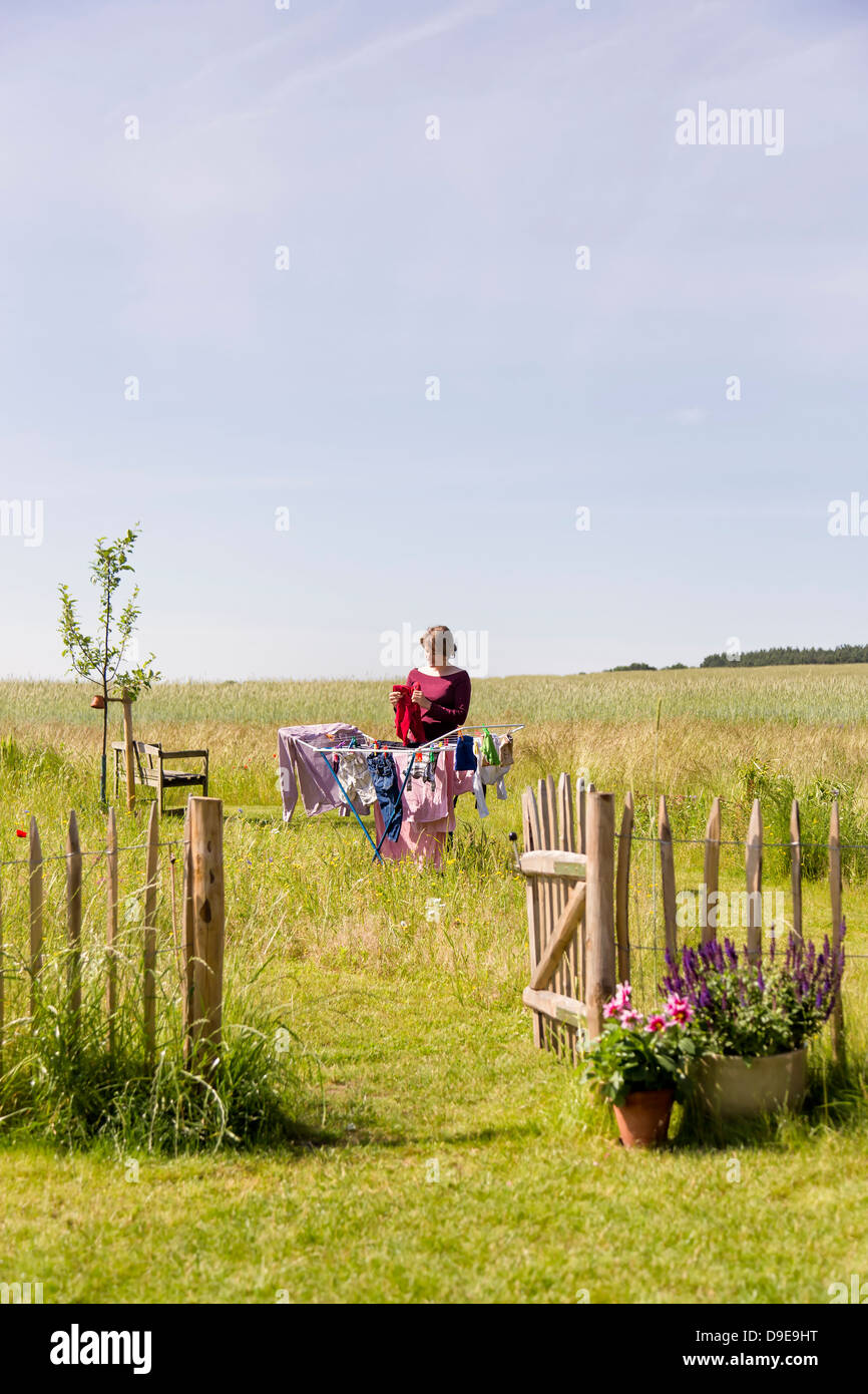 Junge Frau Aufhängen der Wäsche auf einem Wäscheständer in einem ländlichen Garten Stockfoto