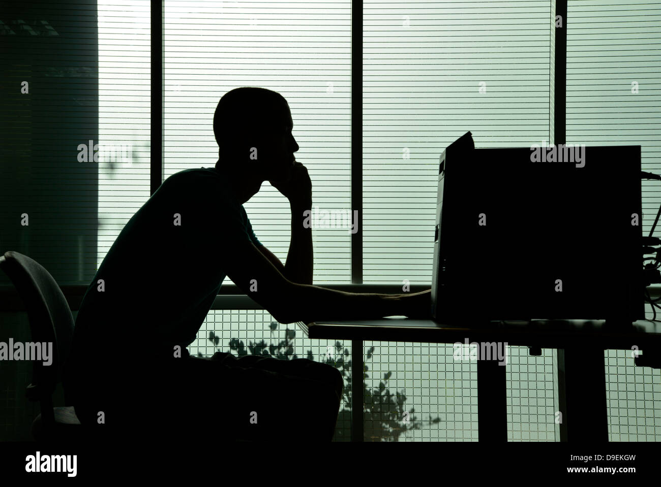 Ein junger Mann arbeitet auf einem Computer in einem Uni-Campus. Stockfoto