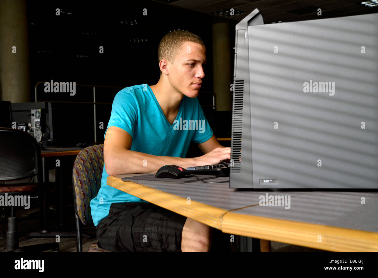 Ein junger Mann arbeitet auf einem Computer in einem Uni-Campus. Stockfoto