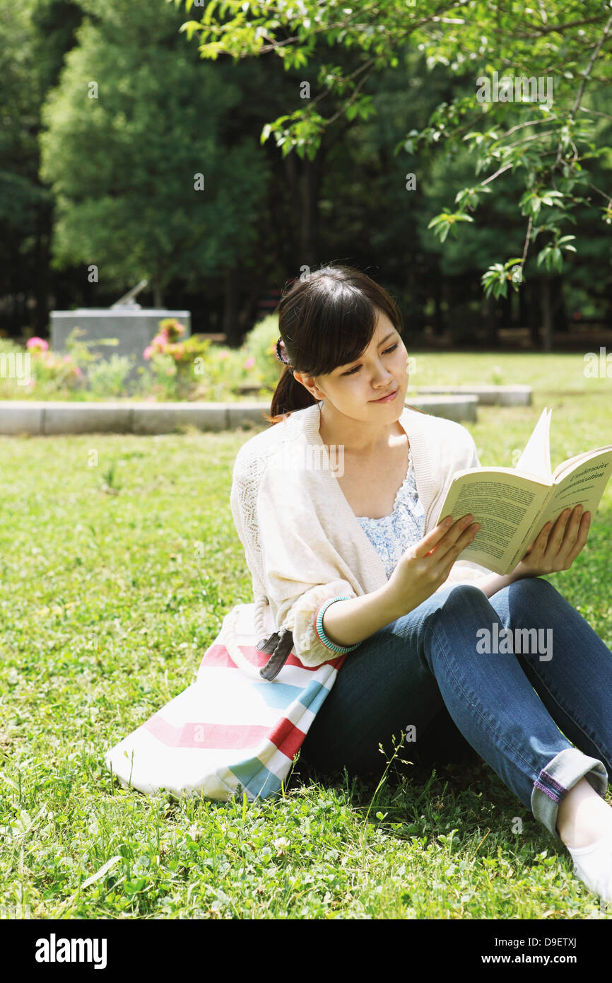 Weibliche College-Studenten Lesen eines Buches auf Grünland Stockfoto