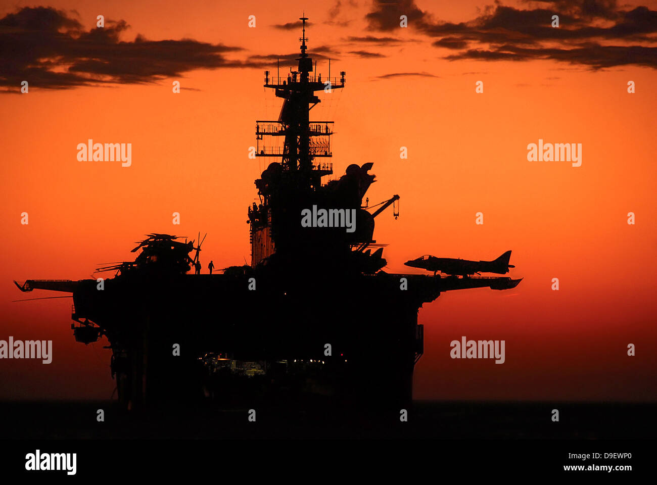 Die untergehende Sonne Silhouetten der amphibischen Angriff Schiff USS Makin Island. Stockfoto