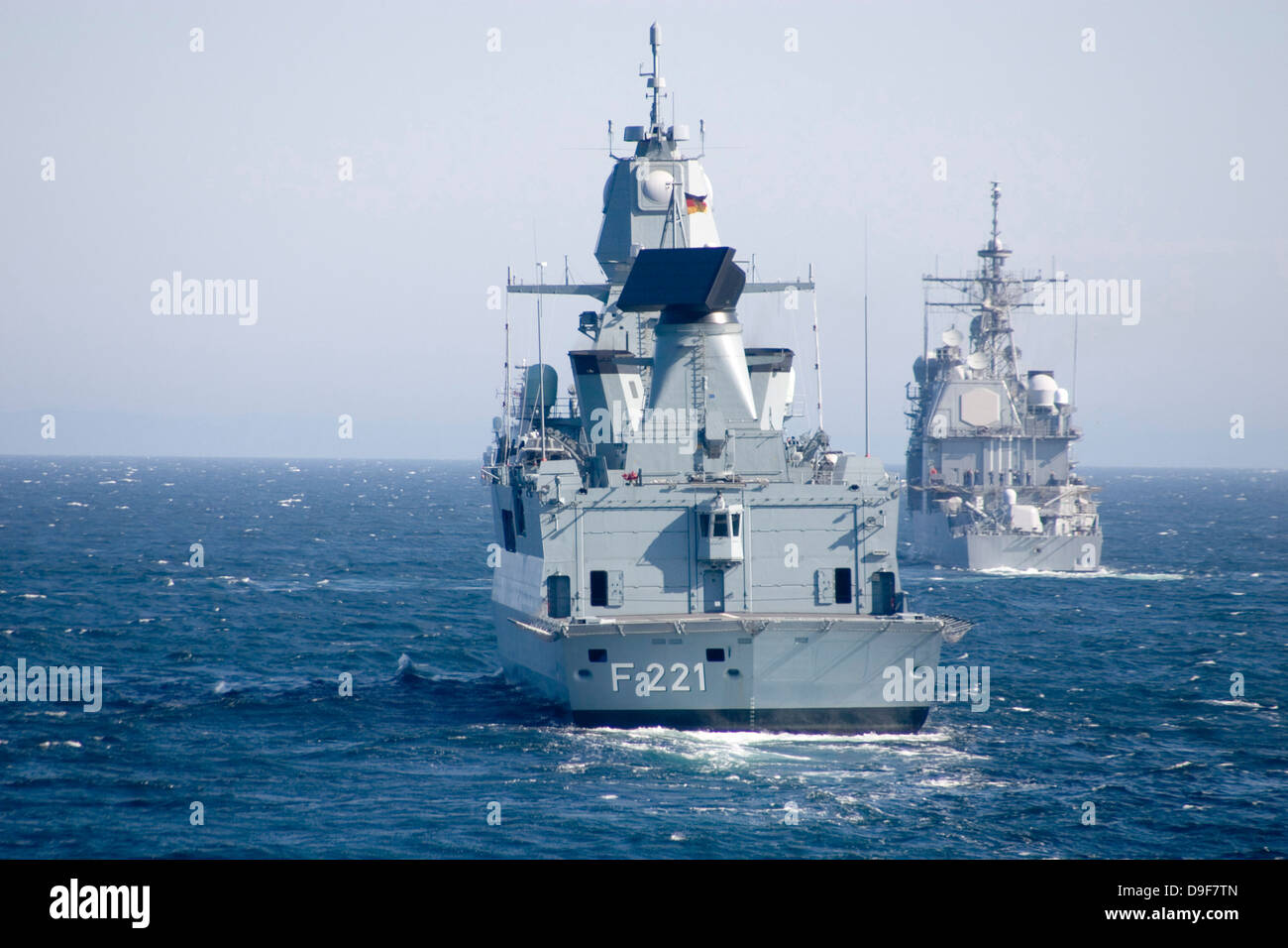 Deutsche Fregatte FFG Hessen und USS Normandy abseits der Küste Schottlands. Stockfoto