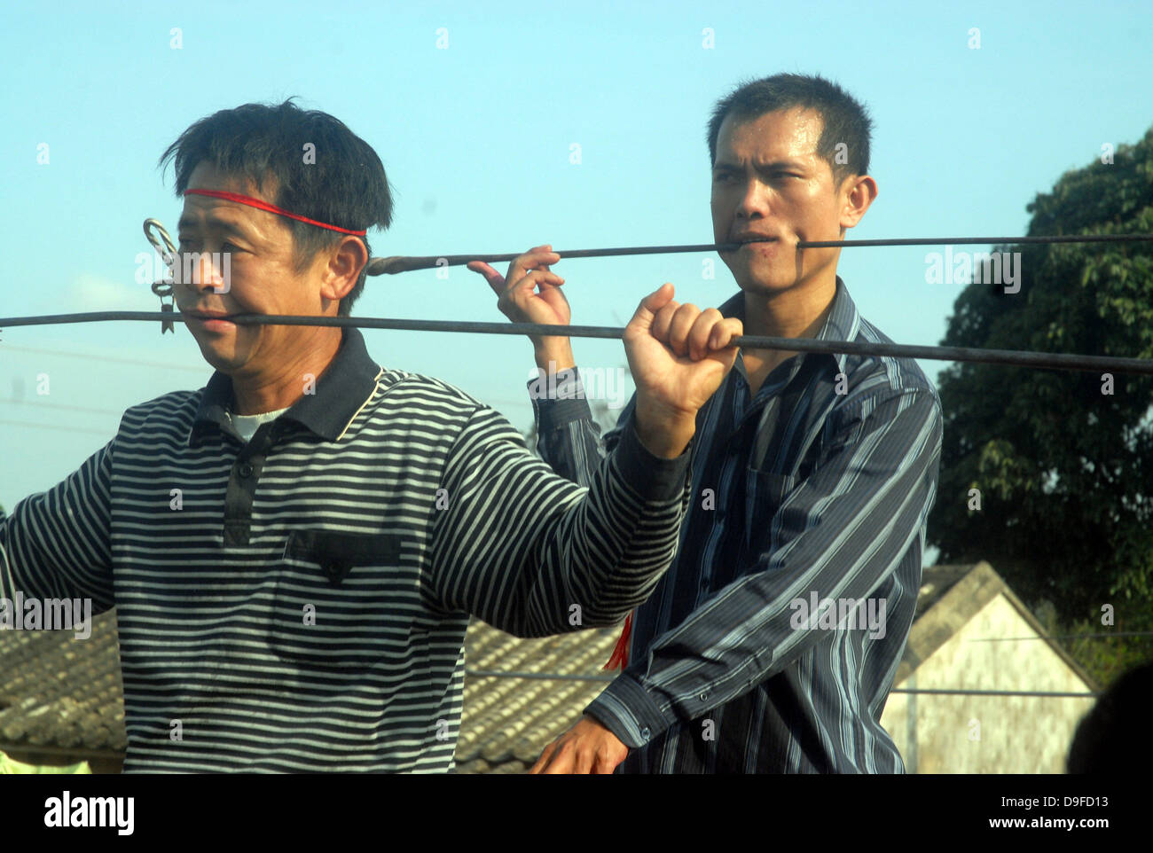 Schmerzhafte Folk Art A besondere Volkskunst Aktivität ist in Ding'an von Haikou, Provinz Hainan, China statt. Die ausführenden durchbohren ihre Wangen mit schweren Eisenstangen und schieben Sie sie auf der anderen Seite ihre Mundwinkel. Die atemberaubende Performance zieht mehr als 10.000 Zuschauer. Sobald die Darsteller Verstümmelung selbst beendet haben, sie entziehen die Eisenstangen und müssen schnell Stockfoto