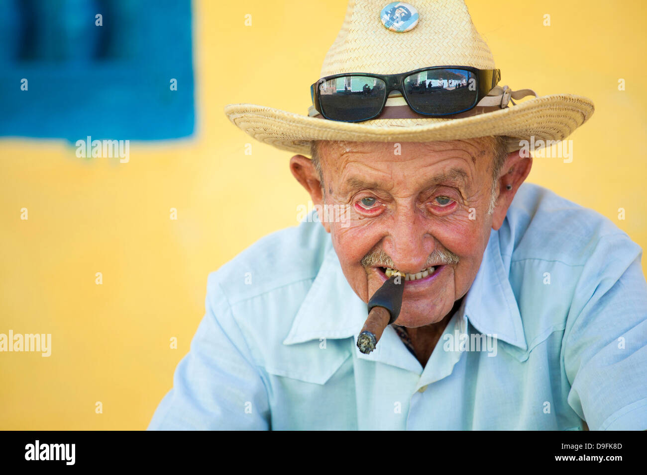 Porträt des alten Mann mit Strohhut posiert vor einer gelben Wand für touristische Pesos, Trinidad, Kuba, West Indies Stockfoto
