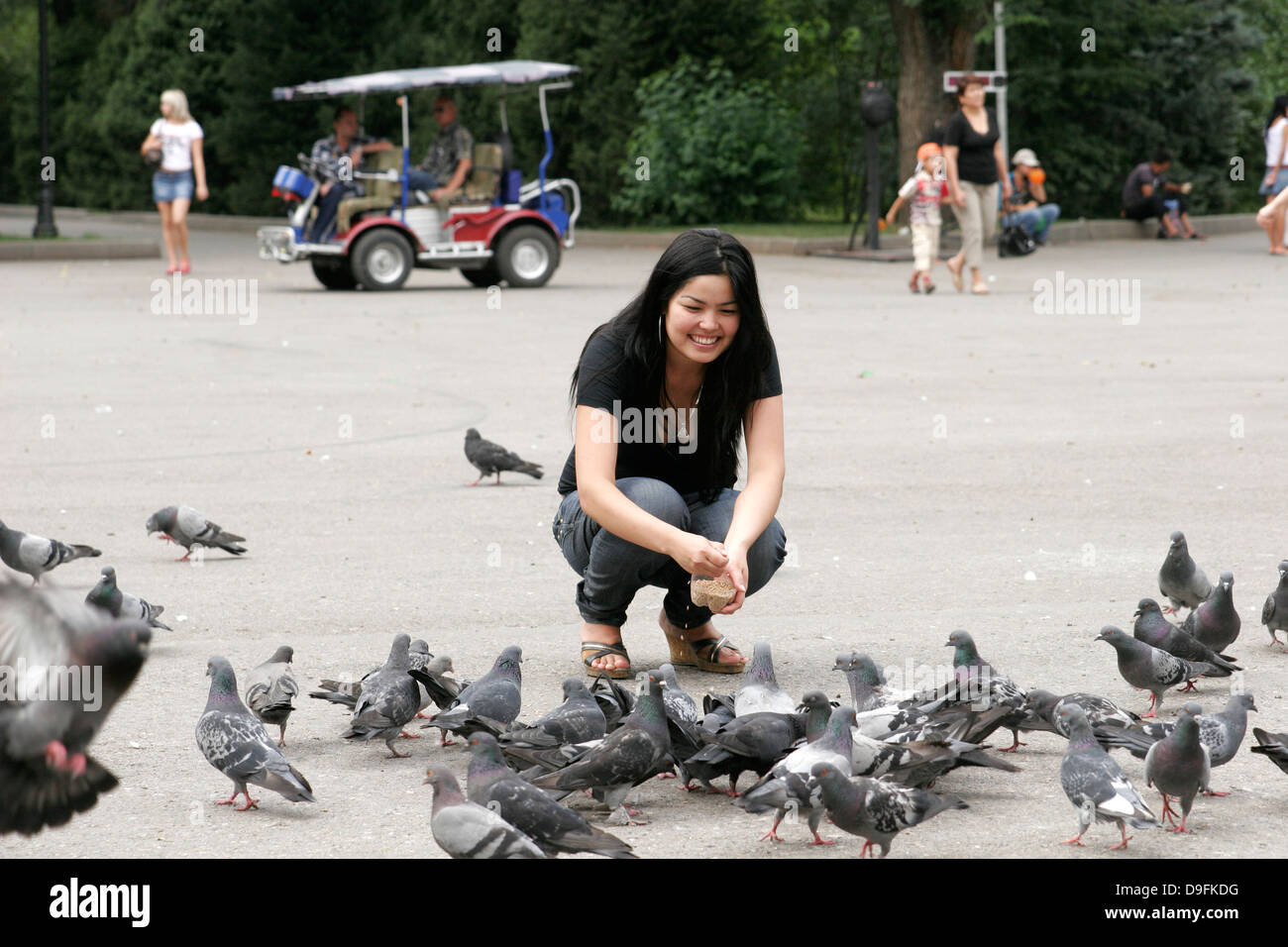 Mädchen füttern Tauben im Park (Panfilov Park), Almaty, Kasachstan, Zentralasien Stockfoto