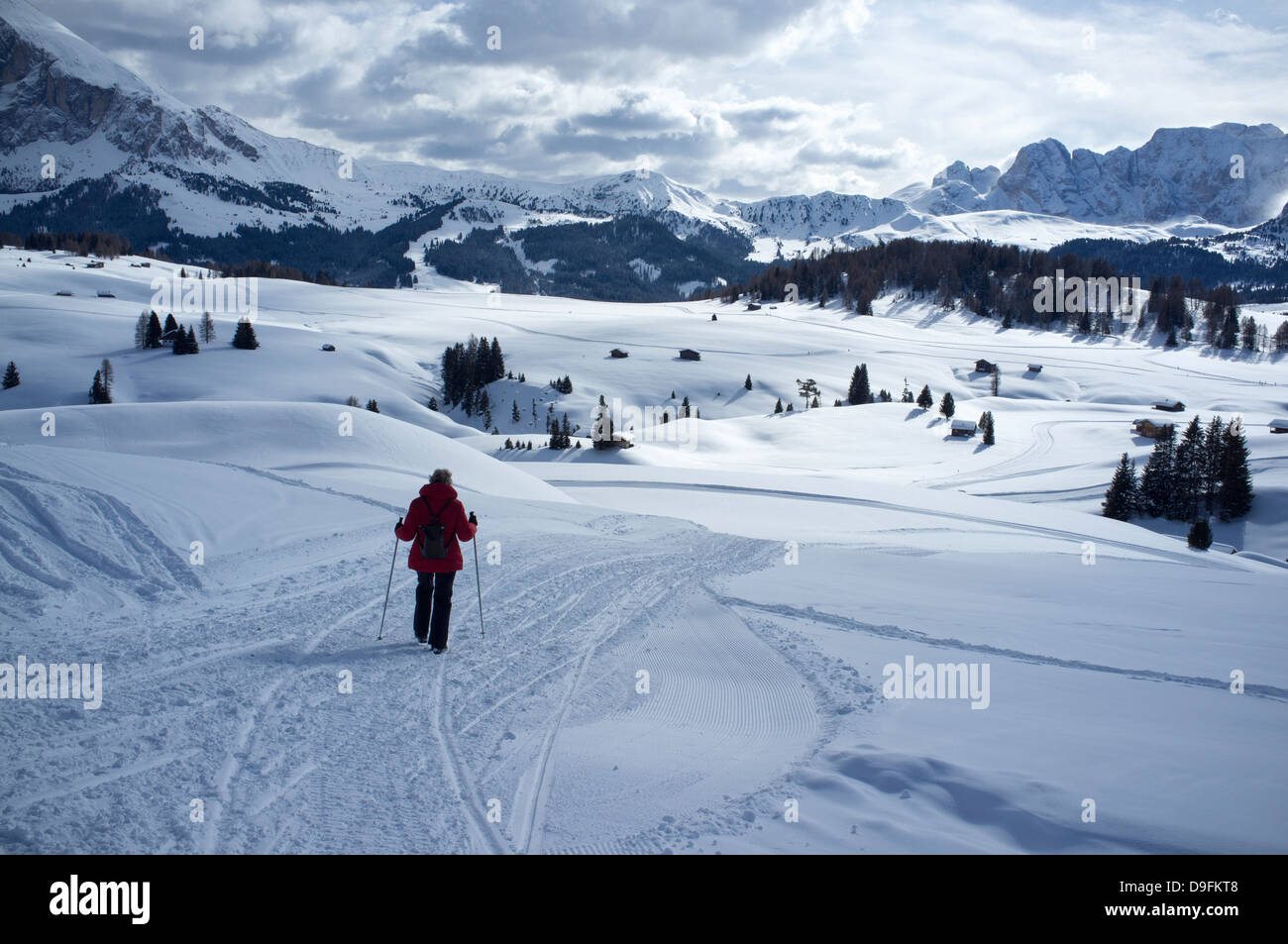 Eine Frau zu Fuß auf einem verschneiten Trail im Alpe di Siusi Skigebiet in der Nähe der Stadt Otisei in den Dolomiten, Südtirol, Italien Stockfoto