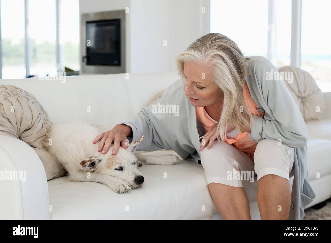 Frau sitzt auf einer Couch mit ihrem Hund Stockfoto
