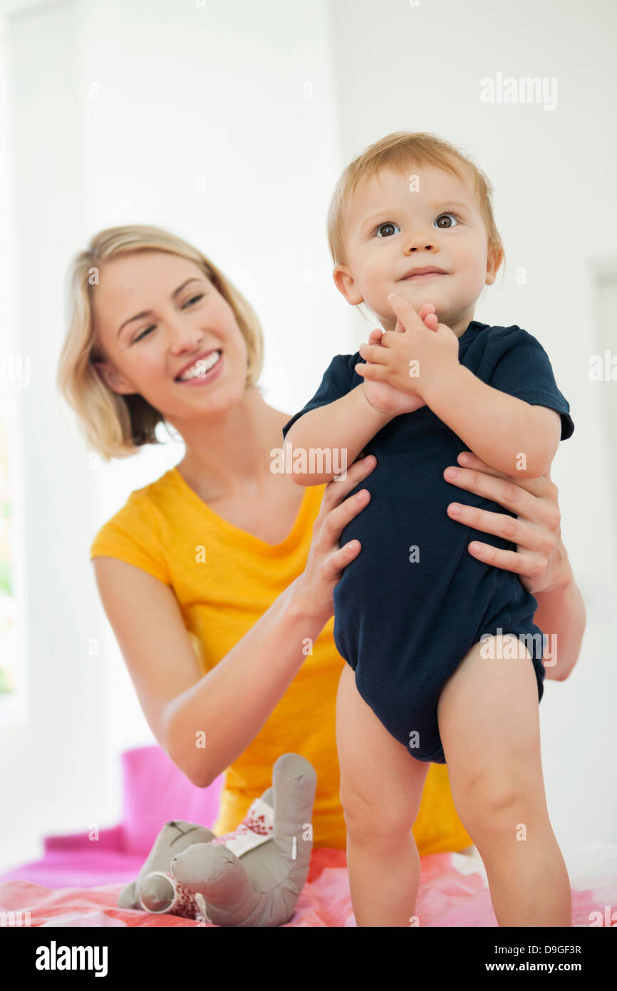 Lächelnde Frau mit ihrem Baby zu spielen, auf dem Bett Stockfoto