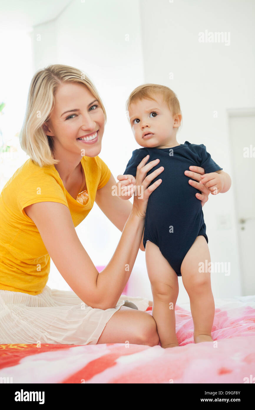 Lächelnde Frau mit ihrem Baby zu spielen, auf dem Bett Stockfoto