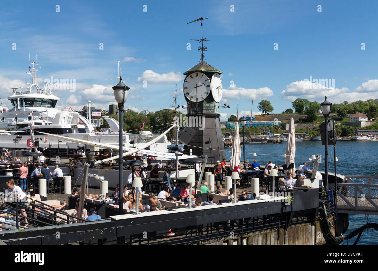 Uhrturm in Europa mit Menschen in Cafés, Norwegen, Oslo Hafen, Pipervika Waterfront Stockfoto