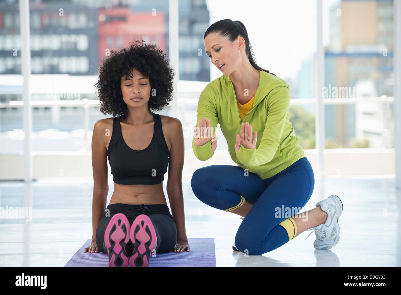 Frau praktizieren Yoga mit Hilfe eines Trainers Stockfoto