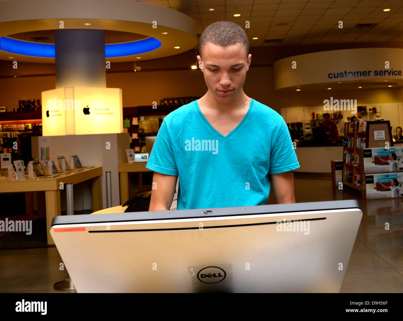 Ein junger Mann schaut von Computern in einer Campus-Buchhandlung. Stockfoto