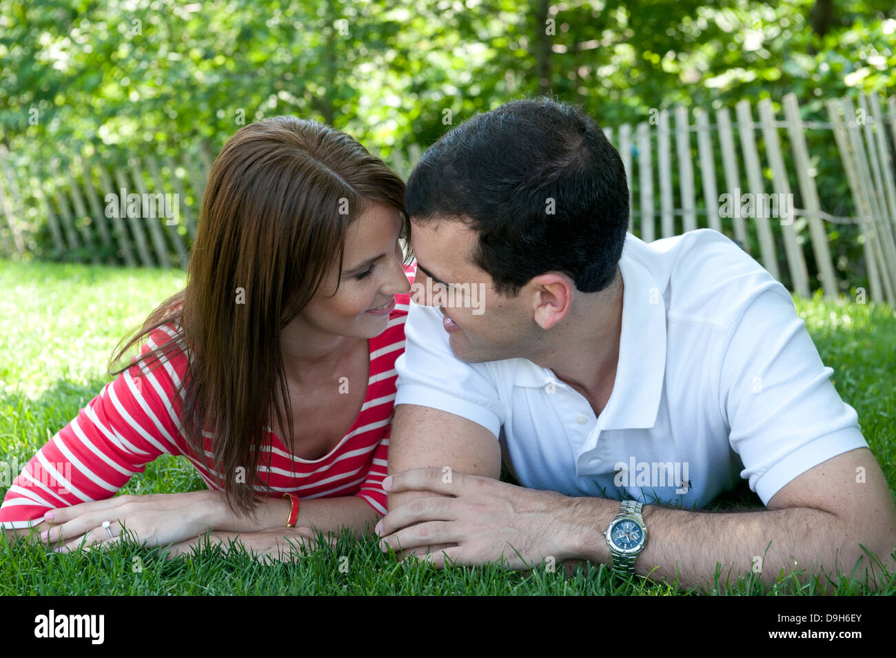 Young Caucasian paar liegen in der Wiese mit Blick auf einander liebevoll Stockfoto