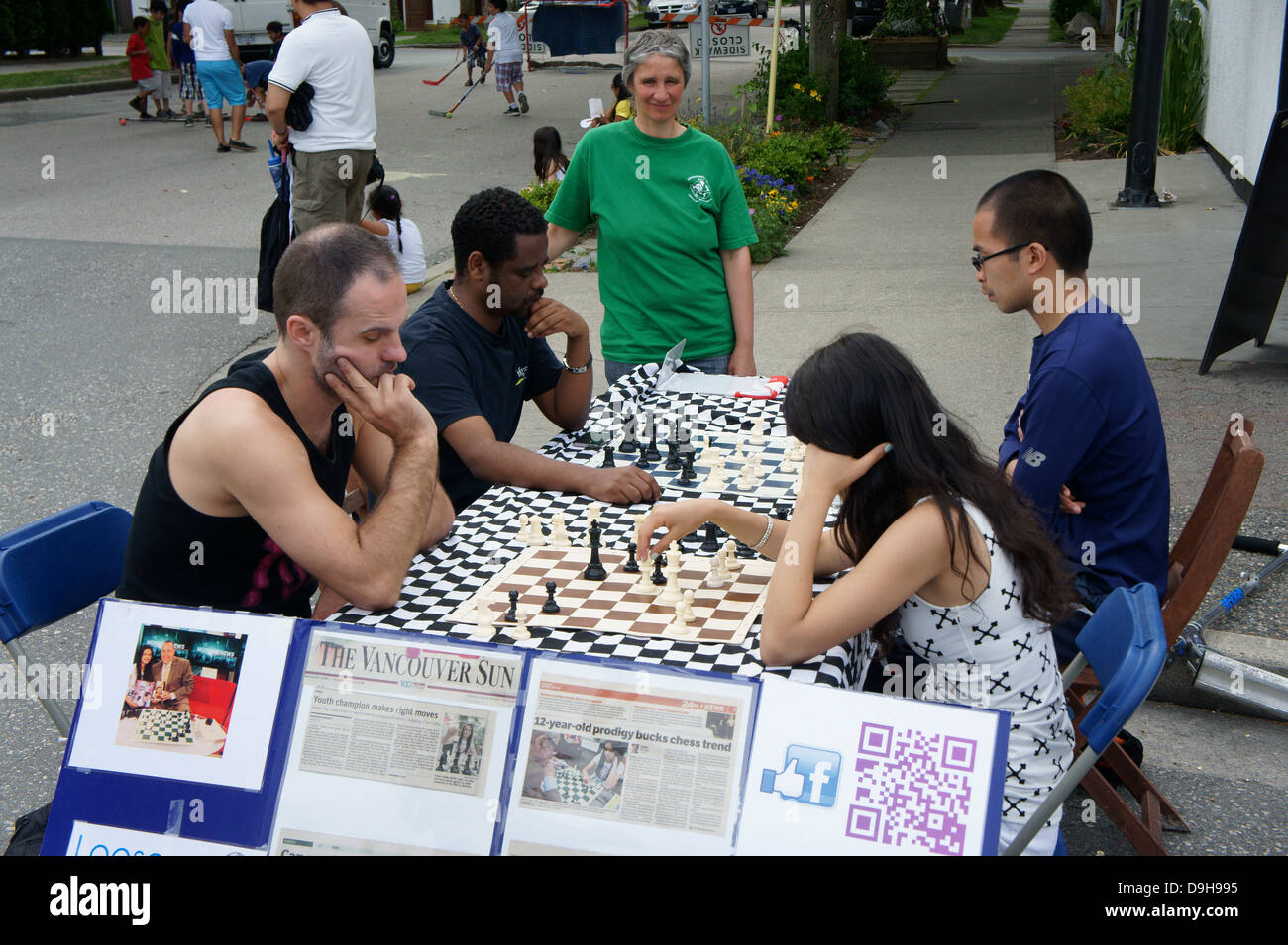 Junge Frau Schachmeister und Menschen verschiedener Rassen spielen Schach im Freien auf der Main Street in Vancouver, BC, Kanada. Stockfoto