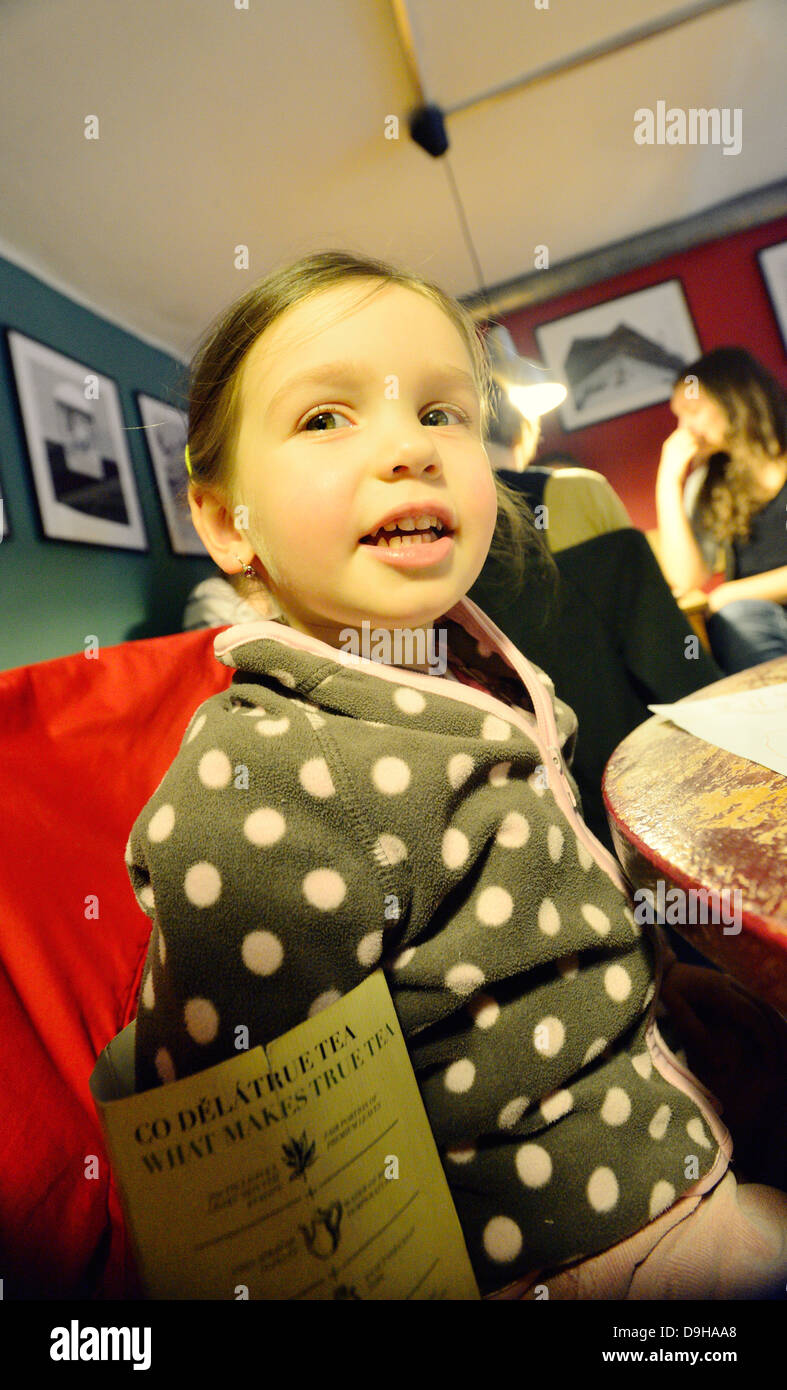 Kleines Mädchen in einem gemütlichen Café, Grimassen Stockfoto