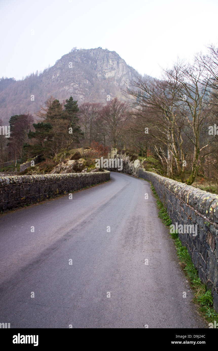 Vertikale stützte. Eine Straße mit Steinmauern Seite geht in den Wald und auf einem entfernten Hügel. Stockfoto