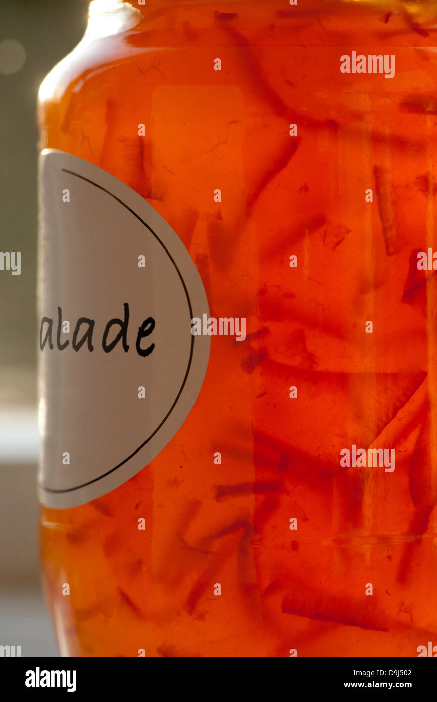Hinterleuchtete Marmelade mit Etikett, auf dem teilweise Orangenschalen zu sehen sind. Kein sichtbares Branding. Stockfoto