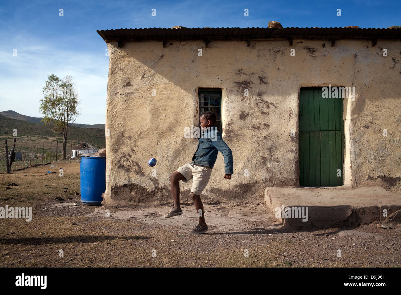 Kleiner Junge übt seine fußballerischen Fähigkeiten mit einem behelfsmäßigen Fußball in ländlichen Transkei, Südafrika Stockfoto