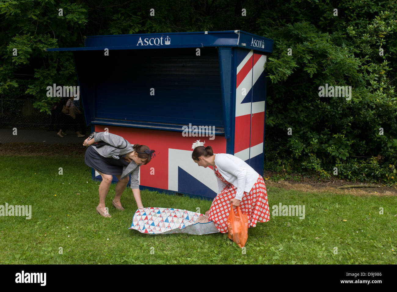 Zwei Damen kommen Sie früh an das Royal Ascot Pferderennen-Festival für einen frühen Picknick auf einem grasbewachsenen Parkplatz. Royal Ascot ist eins von Europas berühmtesten Rennveranstaltungen und stammt aus dem Jahre 1711. Queen Elizabeth und zahlreiche Mitglieder der britischen königlichen Familie zu besuchen. Jedes Jahr im Juni statt, ist es eines der wichtigsten Daten auf den englischen Sportkalender und sozialen Sommersaison. Mehr als 300.000 Menschen stellen den jährlichen Besuch in Berkshire in Royal Ascot Woche machen dieses Europa bestbesuchten Rennveranstaltung mit über 3 Mio. Pfund Preisgeld zu gewinnen. Stockfoto