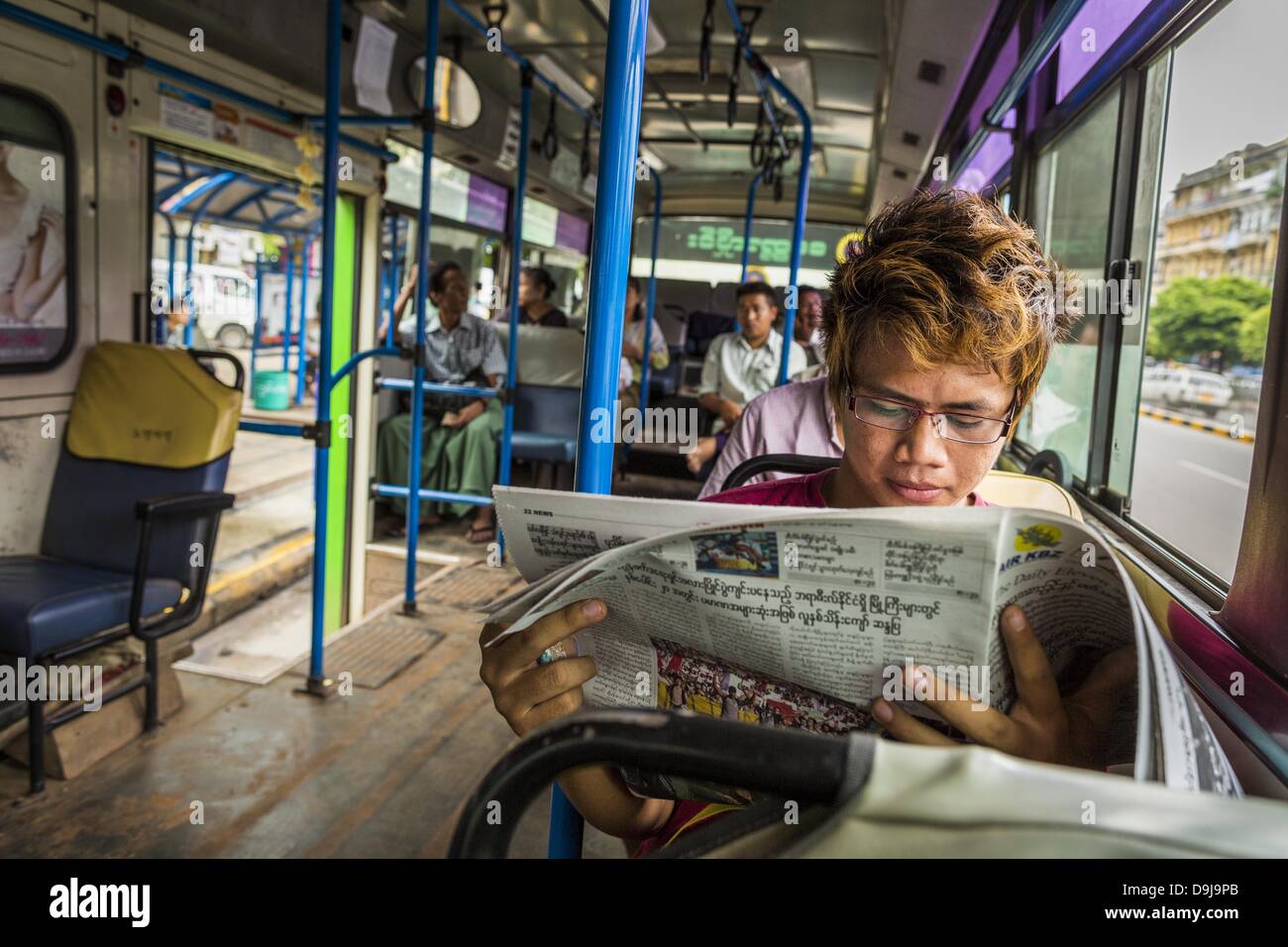 19. Juni 2013 - Yangon, Burma/Myanmar - ein Mann liest eine Zeitung auf einen Bus in Yangon. Die burmesischen Zeitungsindustrie erfreut sich explosive Wachstum in diesem Jahr nach Privateigentum in 2013 durfte. Private Zeitungen wurden geschlossen unter ehemaligen burmesischen Führer Ne Win in den frühen 1960er Jahren. Die revitalisierte private Presse ist ein Zeichen für die dramatischen Veränderungen fegen Myanmar, ehemals Burma, in den letzten drei Jahren. (Bild Kredit: Jack Kurtz/ZUMAPRESS.com ©) Stockfoto