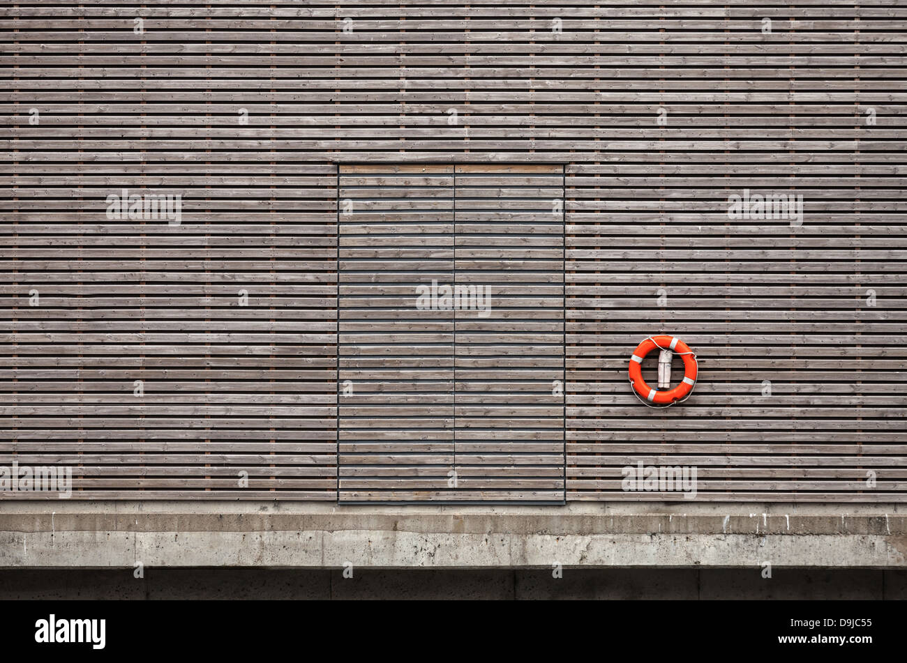 Roten Rettungsring und geschlossener Tür auf verwitterter Holzwand im Hafen Stockfoto