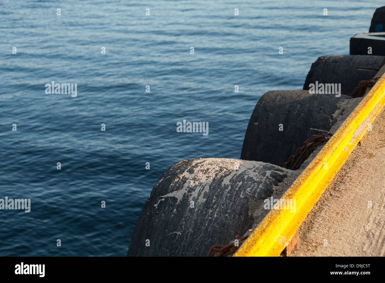 Pier-Fragment mit gelbem Rand und Altreifen als ein Stoßfänger Stockfoto