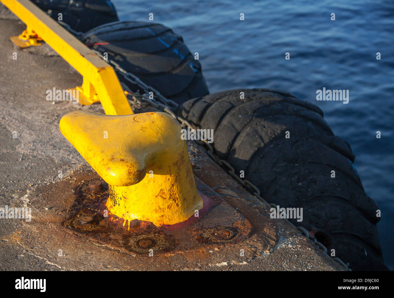 Pier-Fragment mit gelben Borllard und alten Reifen als eine Stoßstangen Stockfoto