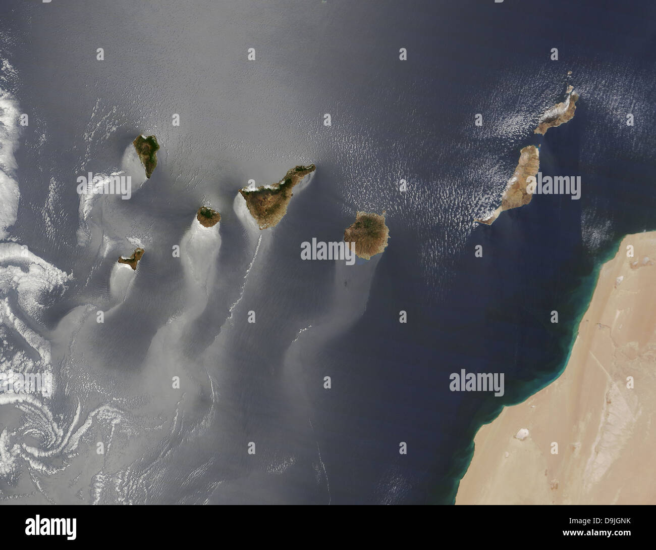 Die Moderate Resolution Imaging Spektroradiometer auf NASA Satelliten Terra blickte auf die milchigen und silbernen Farben erstellt von Sonnenlicht auf die Meeresoberfläche 15. Juni 2013 auf den Kanarischen Inseln. Wellig, Windsack-wie Tails erstrecken sich im Südwesten von einzelnen Inseln. Die Muster sind wahrscheinlich das Ergebnis der Winde Aufrauen oder Glättung der Wasseroberfläche an verschiedenen Orten. Vorherrschende Winde im Bereich kommen aus dem Nordosten und die felsigen, vulkanischen Inseln schaffen eine Art Windschatten-blockieren, verlangsamt und den Luftstrom umleiten. Stockfoto