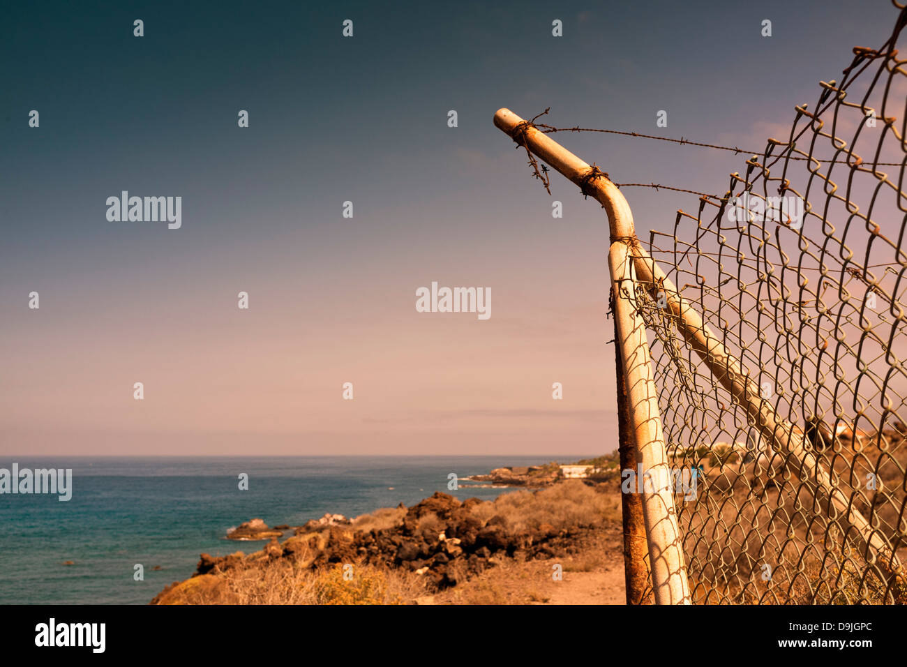 Eckpfosten Maschendraht Zaun mit gebrochenen Stränge aus Stacheldraht oben an der Küste, in der Nähe von Alcala, Teneriffa, Kanarische Inseln, Stockfoto