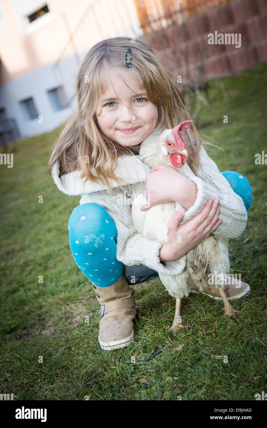 junge Mädchen spielen mit einer Henne auf dem Hinterhof Stockfoto