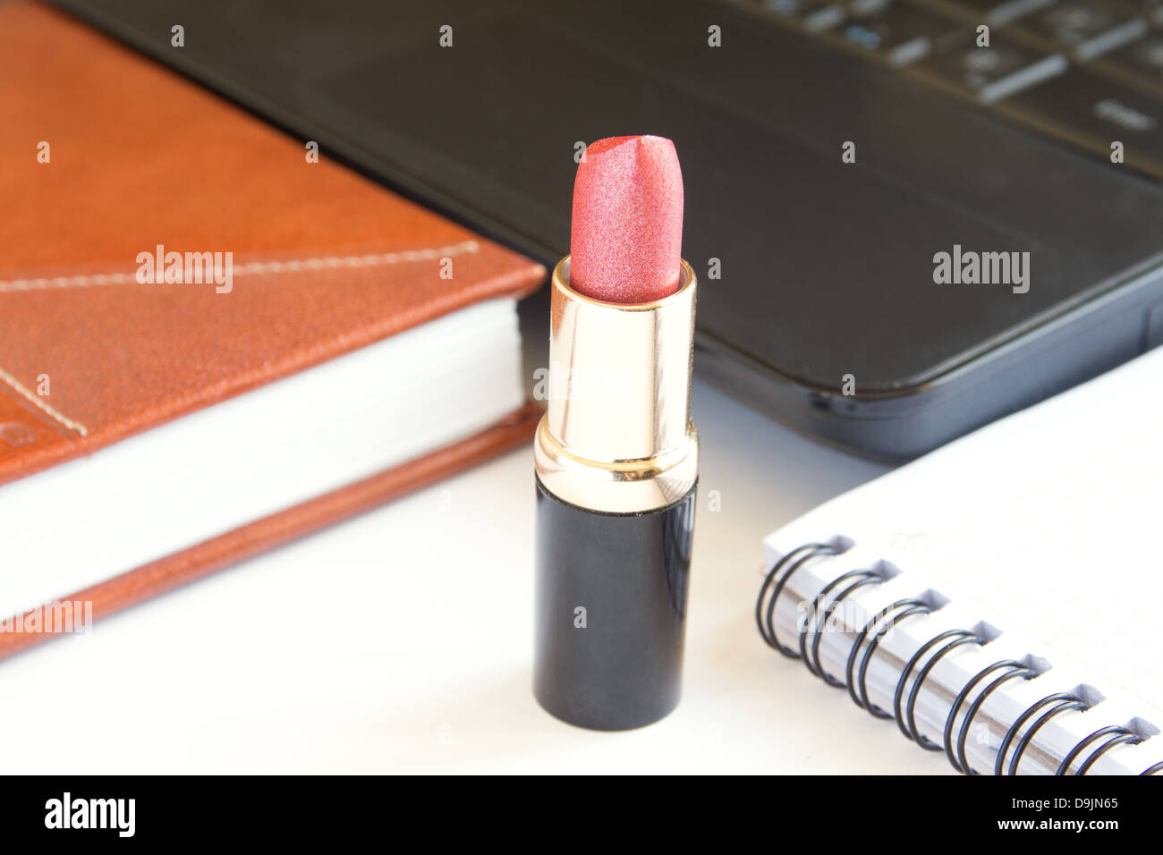 Roter Lippenstift mit Laptop und Notebook am Schreibtisch. Schönheit und Romantik Konzept. Stockfoto