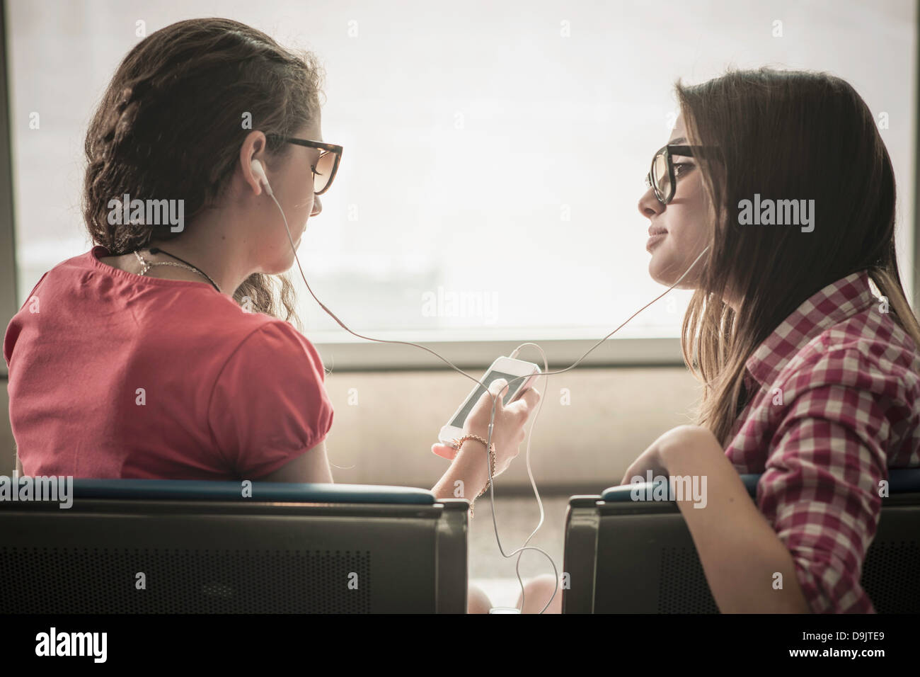Zwei Mädchen im Teenageralter mit Sonnenbrille, Musik hören Stockfoto