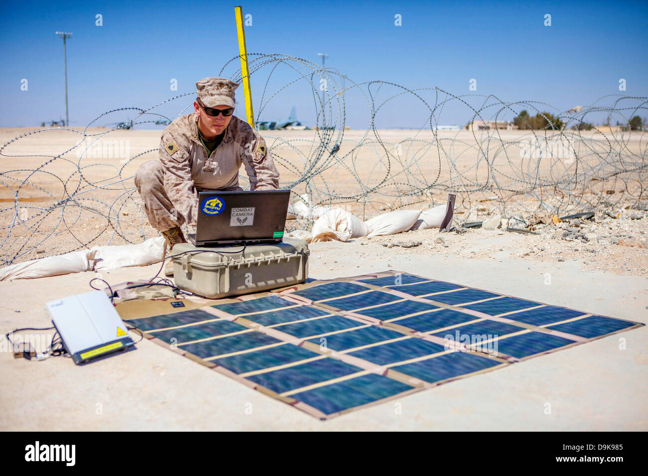 US Marine Fotograf Christopher Q. Stone überträgt Fotos mit einem Broadband Global Area Network Satellitentelefon, angetrieben durch ein Solar Portable Alternative Energie Kommunikationssystem 18. Juni 2013 auf König Faisal Air Base in Jordanien. Stockfoto