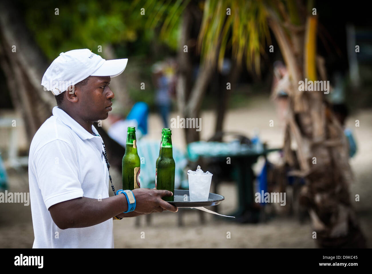 Dominikanische Kellner Bierausschank auf einem exotischen Strand Stockfoto