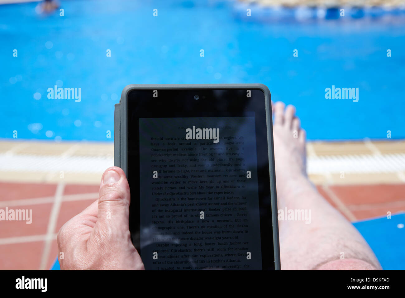 Mann liest Ebook auf dem Tablet-PC an der Seite eines Schwimmbades Urlaub Salou Costa Daurada Spanien Stockfoto