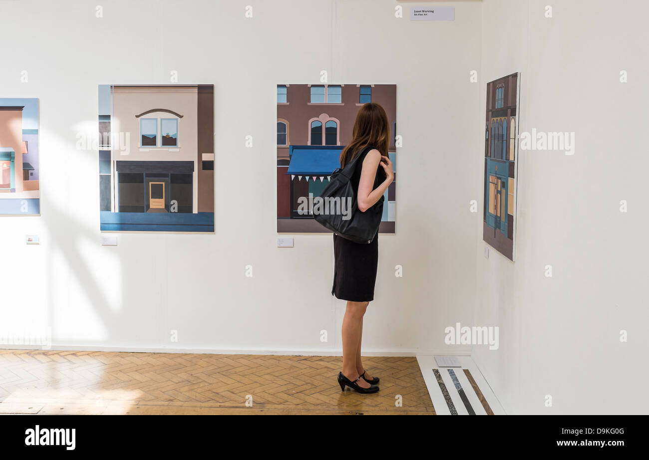 Eine Frau betrachten Gemälde an die Abschluss-Ausstellung in Aberystwyth University School of Art, Wales UK Stockfoto
