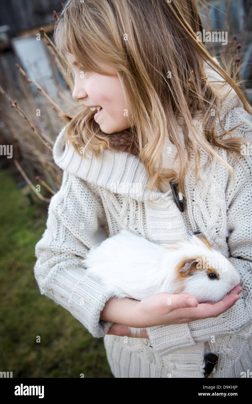 junge Mädchen spielen mit einem Cavia im Garten Stockfoto