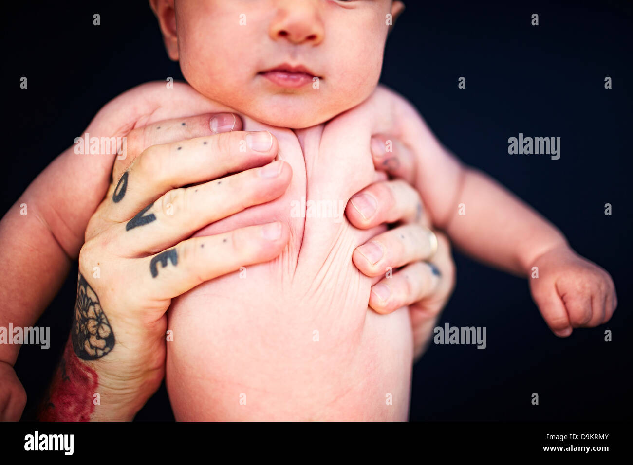 Vater mit tätowierten Händen halten Baby boy Stockfoto