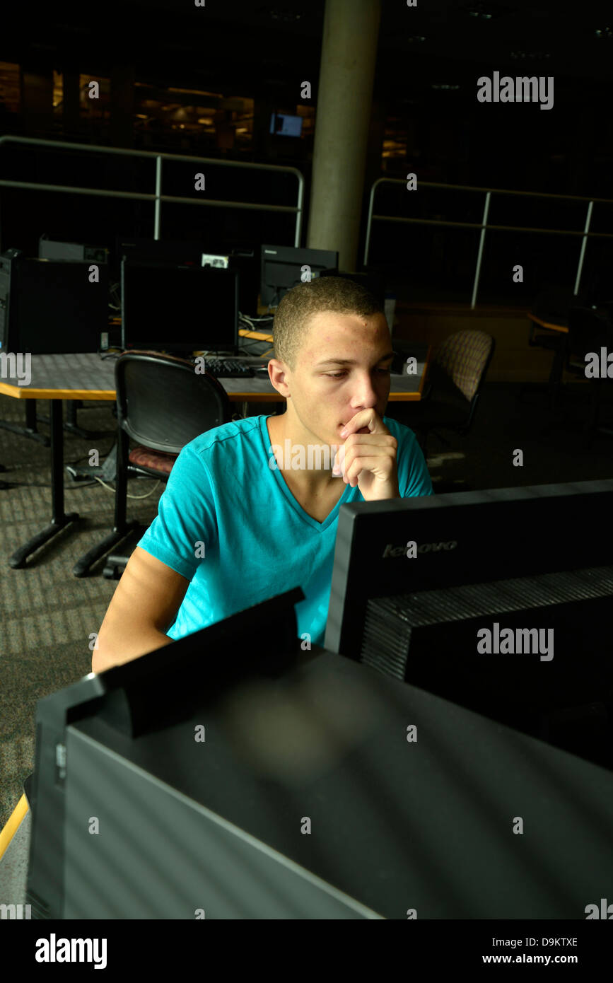 Ein junger Mann arbeitet auf einem Computer in einem Uni-Campus. Stockfoto