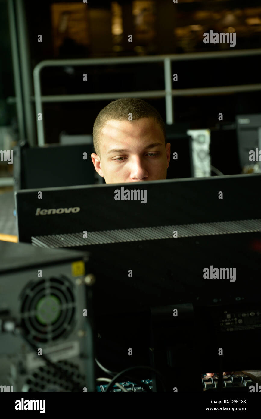 Ein junger Mann arbeitet auf einem Computer in einem Uni-Campus. Stockfoto