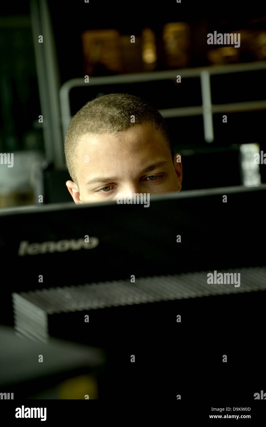 Ein junger Mann arbeitet auf einem Computer in einem Uni-Campus. Stockfoto