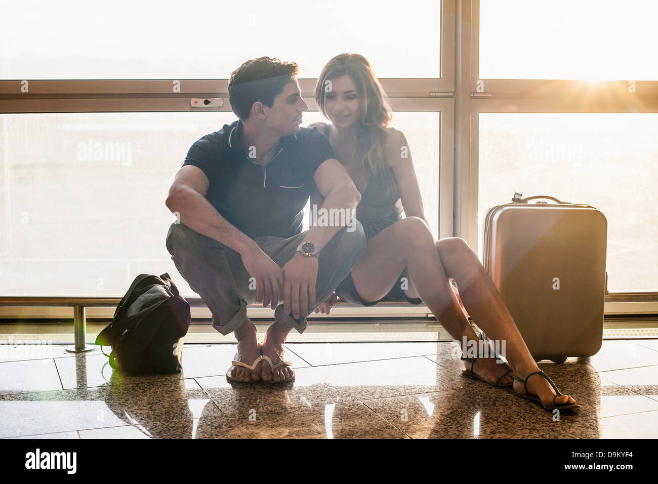Junges Paar sitzt am Geländer in Flughafen Stockfoto
