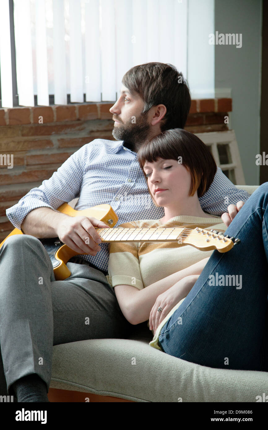 Junge Frau schläft neben Musiker auf sofa Stockfoto