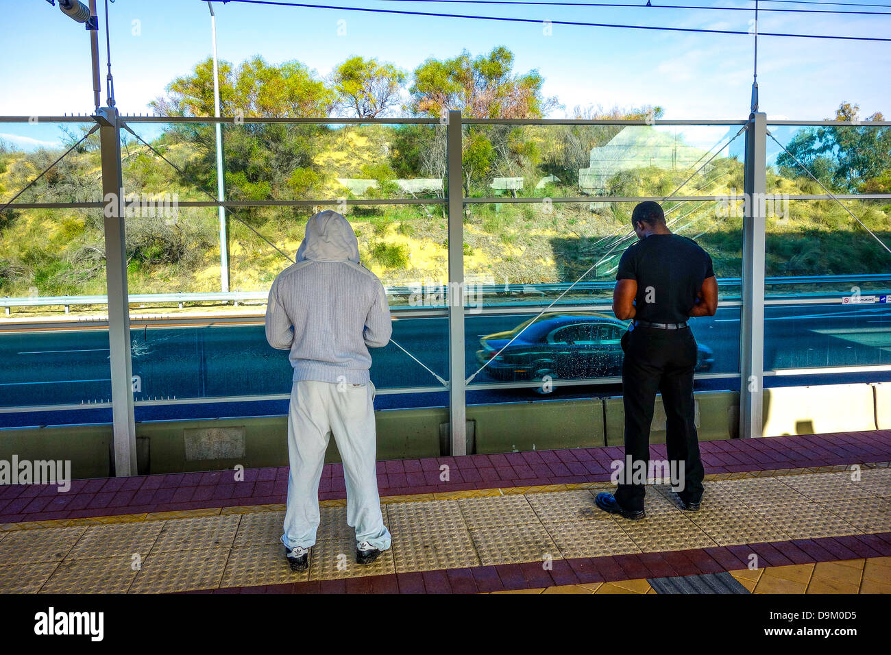 Zwei Passagiere warten auf den Zug am Bahnhof. Gekleidet in schwarz / weiß Stockfoto