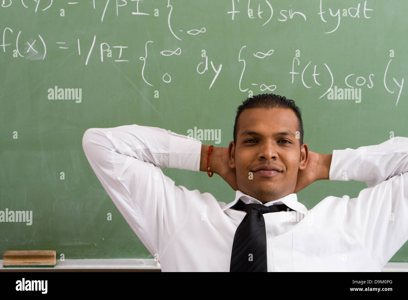 zuversichtlich Mathelehrer sitzen vor Tafel Stockfoto