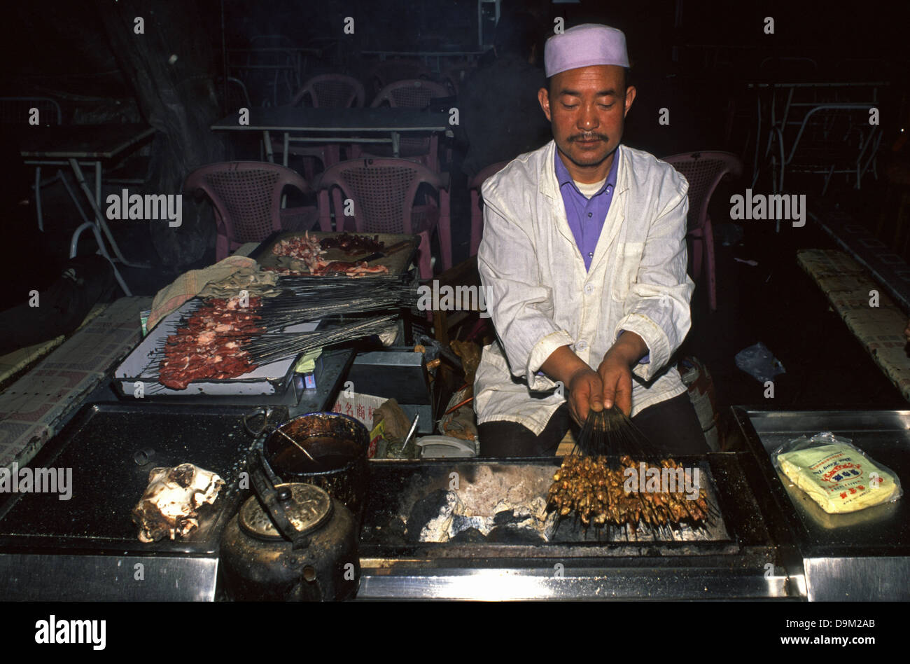 Ein Hui muslimischen Mann grillen Fleisch bei einem Essen in der Nacht Markt der Jiiayuguan eine Stadt in der nordwestlichen Provinz Gansu China Abschaltdruck Stockfoto Ein Hui muslimischen Mann grillen Fleisch bei einem Essen in der Nacht Markt der Jiiayuguan eine Stadt in der nordwestlichen Provinz Gansu China Abschaltdruck Stockfoto