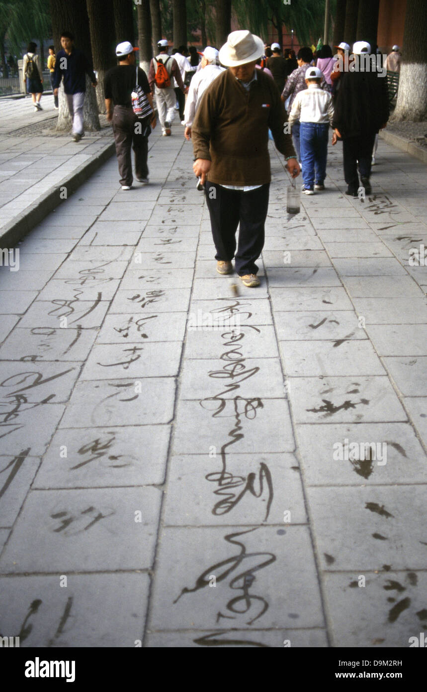Ein Mann nutzt einen manipulierten riesigen Pinsel Tinte Wasser verdunstet wie Kalligraphie, die verschwindende Tinte auf der Fahrbahn in Summer Palace Beijing China zu schreiben. Stockfoto Ein Mann nutzt einen manipulierten riesigen Pinsel Tinte Wasser verdunstet wie Kalligraphie, die verschwindende Tinte auf der Fahrbahn in Summer Palace Beijing China zu schreiben. Stockfoto