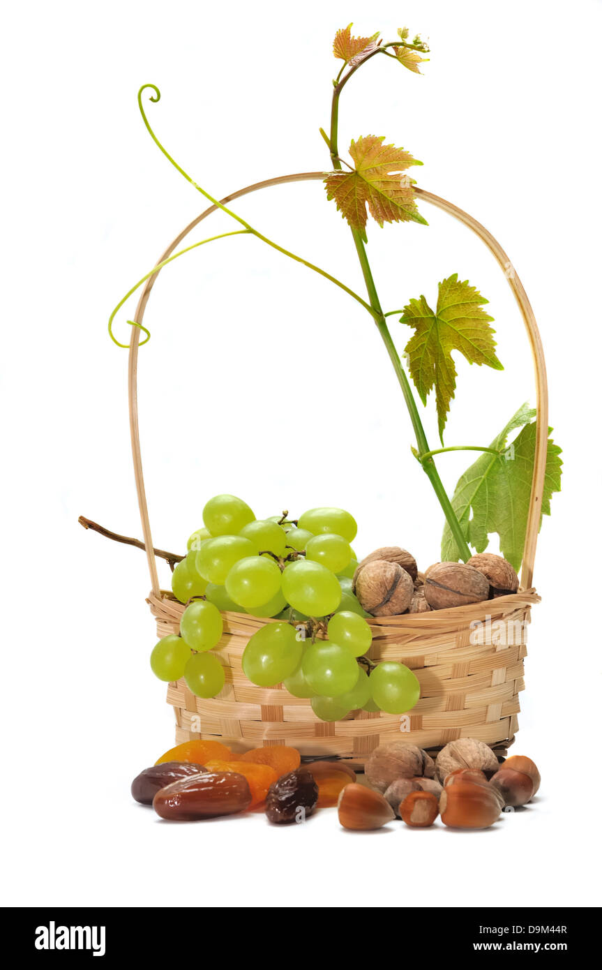 Trauben in einen kleinen Korb mit Laub und getrockneten Nüssen auf weißem Hintergrund Stockfoto